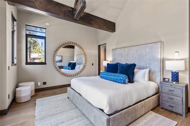 bedroom featuring beamed ceiling and light wood-type flooring