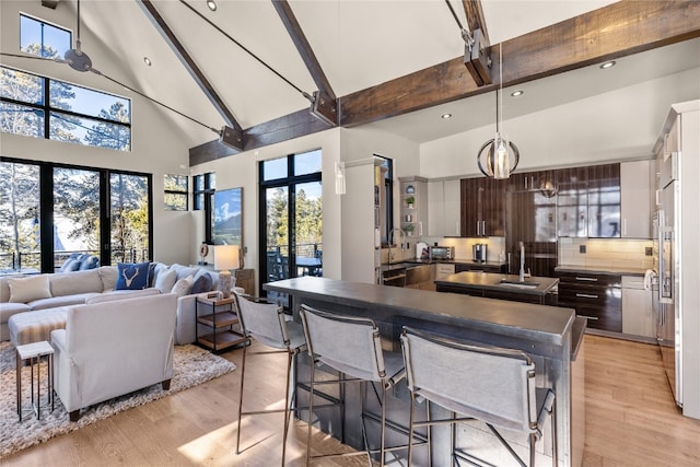 kitchen with beam ceiling, dark brown cabinetry, backsplash, and high vaulted ceiling