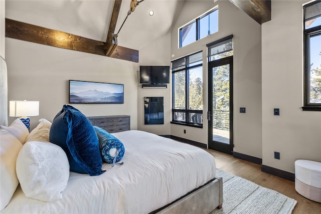 bedroom featuring beam ceiling, access to outside, and light hardwood / wood-style floors