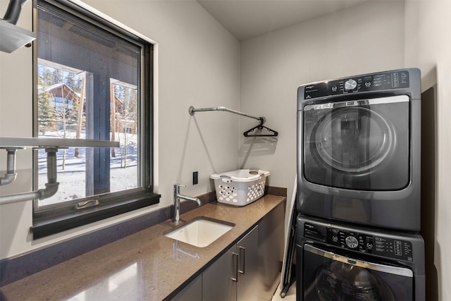 laundry area featuring cabinets, stacked washer / dryer, and sink