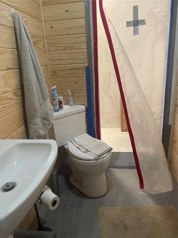 bathroom featuring tile patterned flooring, a sink, a shower stall, and toilet
