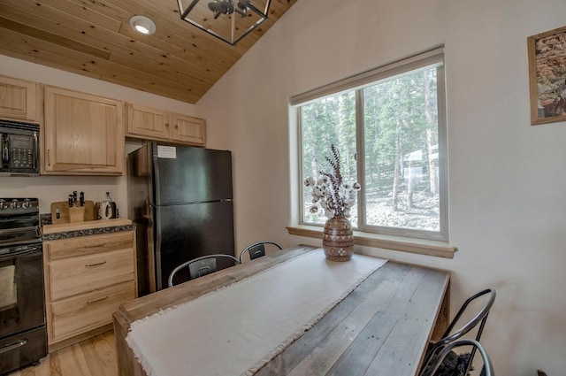 kitchen with light wood finished floors, light brown cabinetry, light countertops, vaulted ceiling, and black appliances