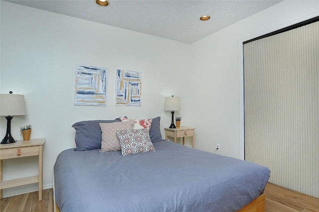 bedroom featuring light wood-style floors, a textured ceiling, and baseboards