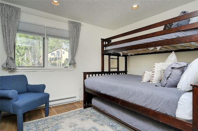 bedroom featuring a baseboard radiator, wood finished floors, a textured ceiling, and recessed lighting