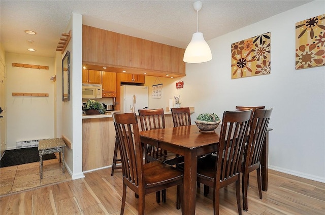dining area featuring a textured ceiling, light wood-type flooring, baseboards, recessed lighting, and a baseboard radiator