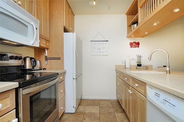 kitchen featuring light countertops, a sink, white appliances, stone tile flooring, and baseboards