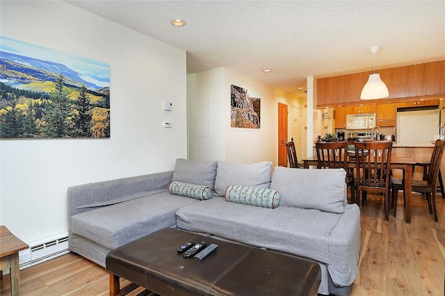 living area with a baseboard heating unit, a textured ceiling, light wood finished floors, and recessed lighting