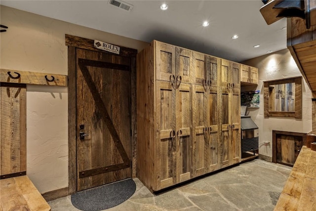 interior space featuring a textured wall, visible vents, and recessed lighting