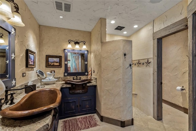 bathroom with double vanity, visible vents, a walk in shower, and a sink