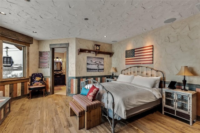 bedroom with hardwood / wood-style flooring, connected bathroom, and recessed lighting