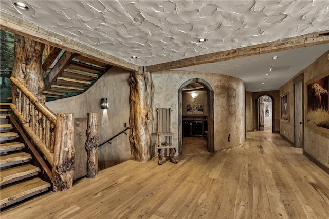 interior space with stairway, wood-type flooring, and arched walkways