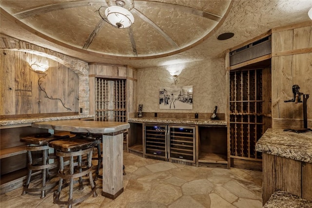 wine cellar with wine cooler, stone finish floor, and a dry bar