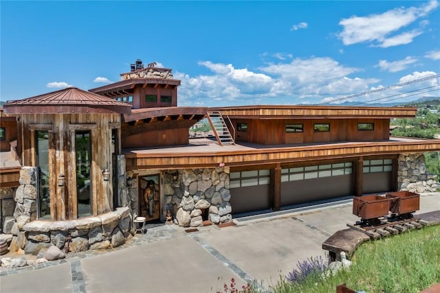 view of front of property featuring an attached garage, stone siding, and concrete driveway