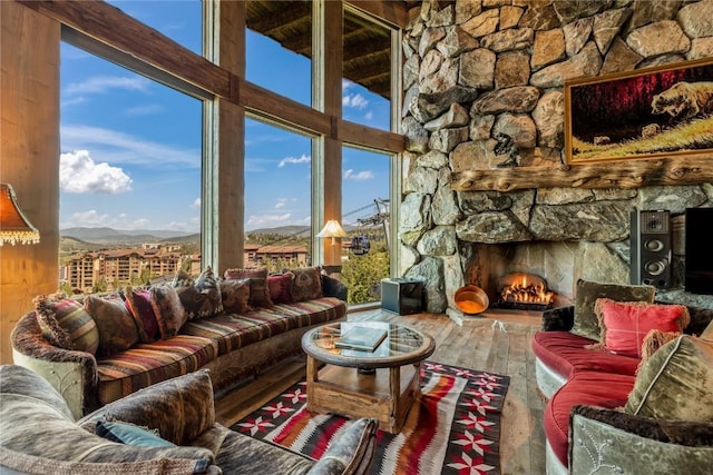 living room with hardwood / wood-style flooring, a stone fireplace, and a mountain view