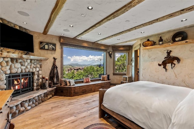 bedroom with recessed lighting, beam ceiling, a fireplace, and wood-type flooring