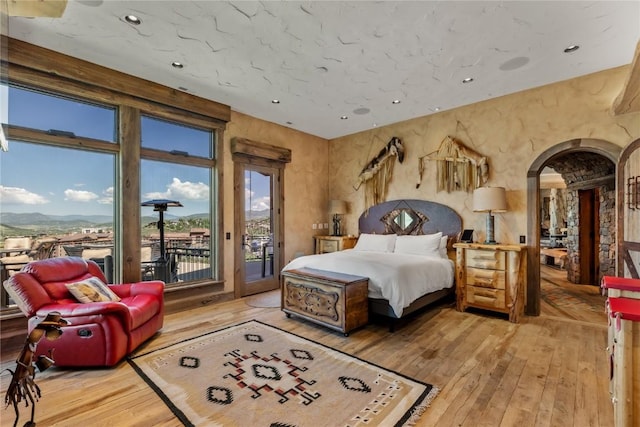 bedroom featuring arched walkways, access to outside, hardwood / wood-style floors, and recessed lighting