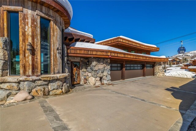 snow covered property featuring stone siding and a mountain view