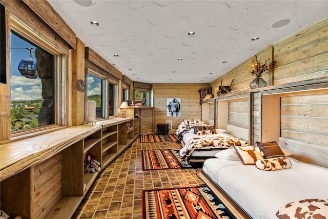 bedroom featuring brick floor, recessed lighting, multiple windows, and wooden walls