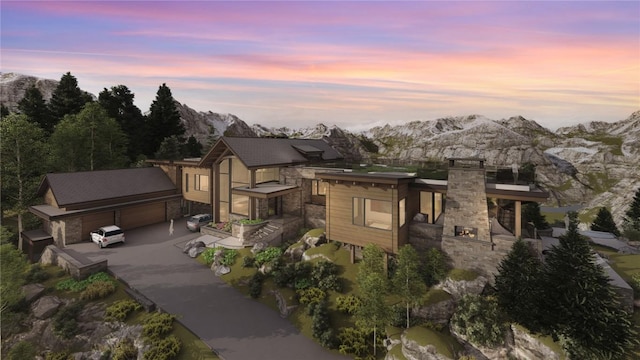 view of front of property featuring concrete driveway, a mountain view, and stone siding
