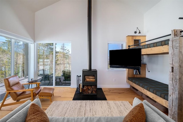 21185 County Road 16, Oak Creek, CO 80467 - living area featuring baseboards, a wood stove, light wood finished floors, and a high ceiling
