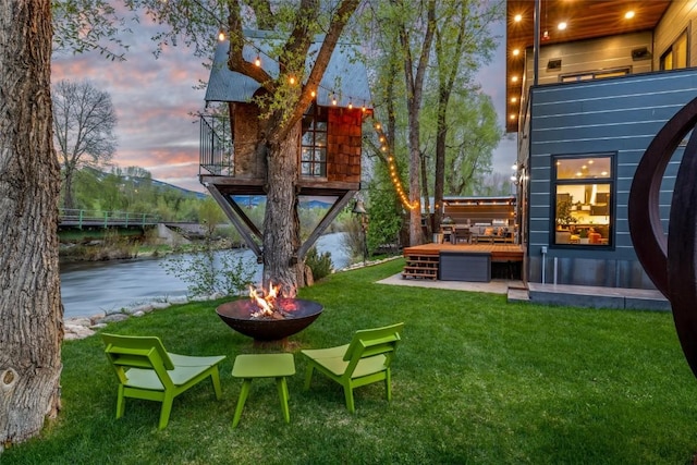 410 River Rd, Steamboat Springs, CO 80487 - view of green lawn with an outdoor fire pit and a deck with water view