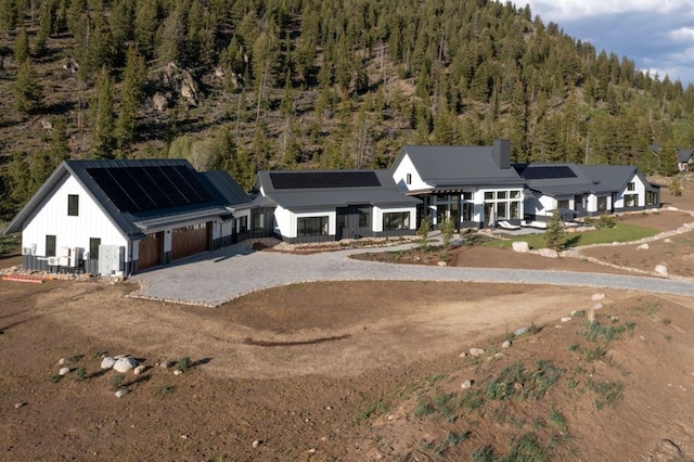 403 Revett Dr, Breckenridge, CO 80424 - view of front facade featuring a wooded view, roof mounted solar panels, driveway, and board and batten siding