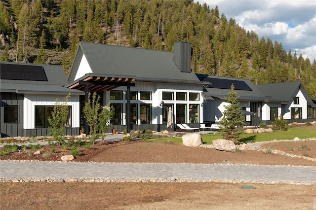 403 Revett Dr, Breckenridge, CO 80424 - modern inspired farmhouse with board and batten siding, solar panels, a chimney, and a wooded view