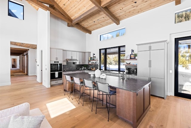 403 Revett Dr, Breckenridge, CO 80424 - kitchen featuring stainless steel double oven, high vaulted ceiling, a breakfast bar area, light wood finished floors, and tasteful backsplash