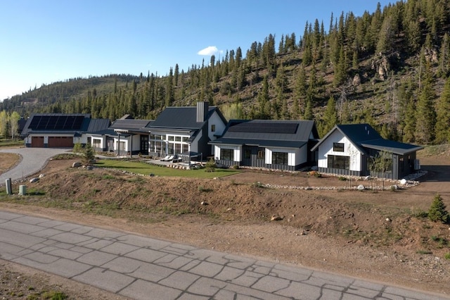 403 Revett Dr, Breckenridge, CO 80424 - view of front facade with roof mounted solar panels, a view of trees, a metal roof, and an attached garage