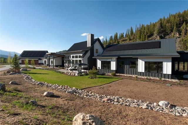 403 Revett Dr, Breckenridge, CO 80424 - rear view of property featuring board and batten siding, a chimney, a lawn, and solar panels