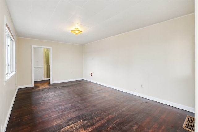 spare room featuring baseboards, dark wood finished floors, and visible vents