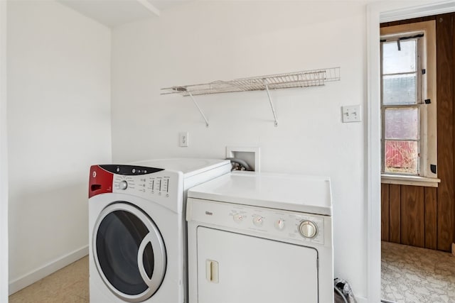 laundry room with washing machine and clothes dryer, wood walls, baseboards, and laundry area