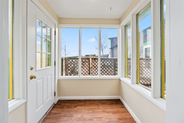unfurnished sunroom featuring wood finished floors and baseboards