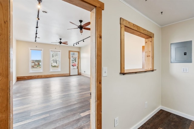 corridor with electric panel, rail lighting, dark wood finished floors, crown molding, and baseboards
