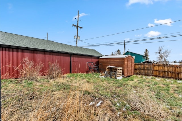 view of yard with an outdoor structure, a shed, and fence