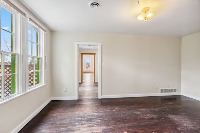 unfurnished room with visible vents, wood finished floors, and baseboards