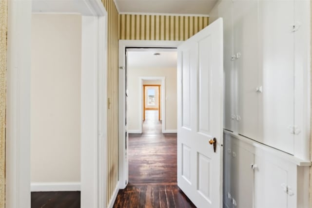 corridor featuring wallpapered walls, dark wood finished floors, and baseboards