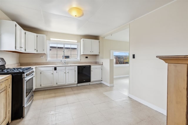 kitchen featuring dishwasher, light countertops, stainless steel gas range oven, and white cabinetry