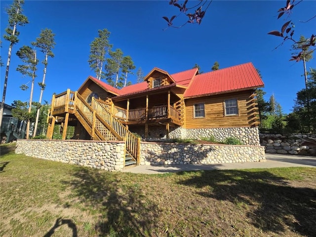 rear view of property featuring stairway, a lawn, a deck, log siding, and metal roof