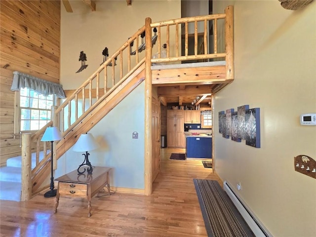 stairs featuring baseboard heating, a healthy amount of sunlight, and wood finished floors