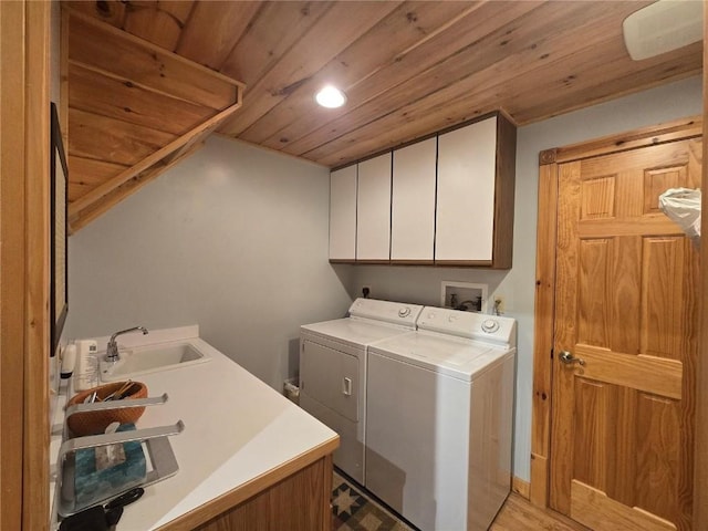 washroom with light wood finished floors, a sink, cabinet space, wooden ceiling, and washer and dryer