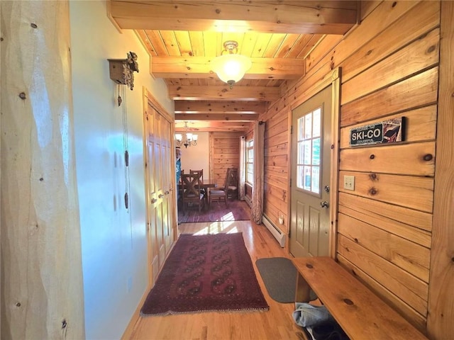 hall with a baseboard radiator, wood finished floors, wooden ceiling, wood walls, and beam ceiling