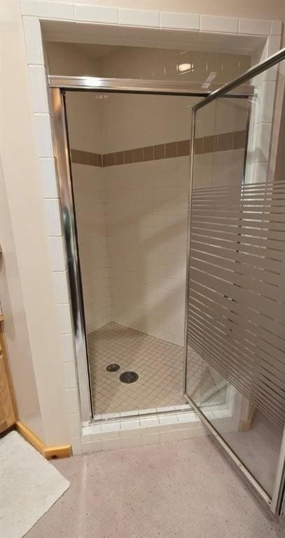 bathroom with speckled floor and a stall shower