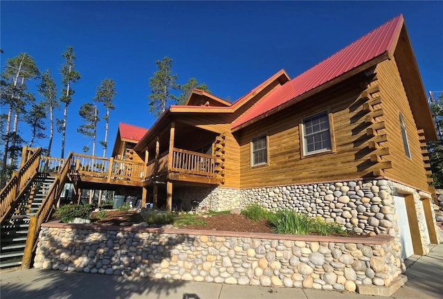 back of house featuring metal roof, stairway, log siding, and a deck