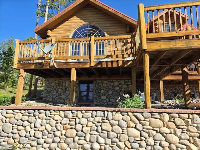back of property with stone siding and a wooden deck