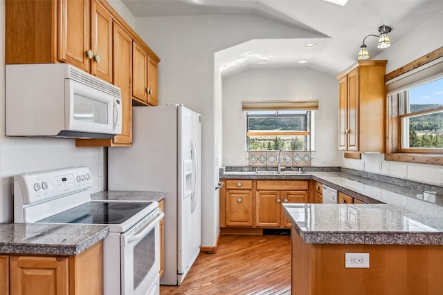kitchen with vaulted ceiling, tile counters, a sink, white appliances, and light wood finished floors