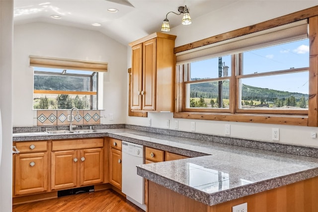 kitchen with tile counters, light wood-style flooring, a sink, vaulted ceiling, and dishwasher
