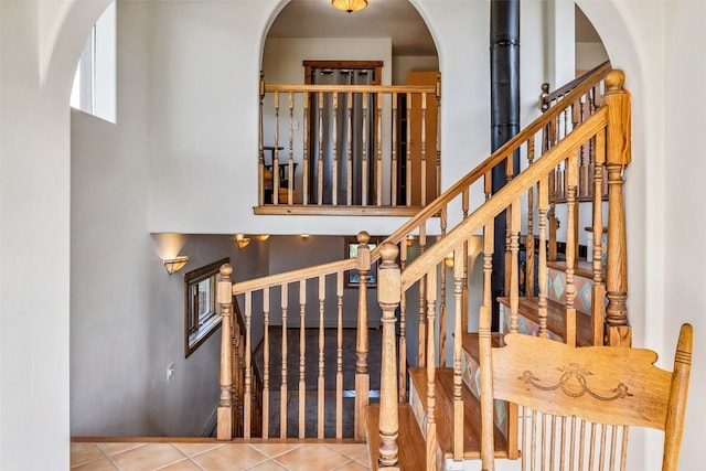 stairs featuring arched walkways, baseboards, a high ceiling, and tile patterned flooring