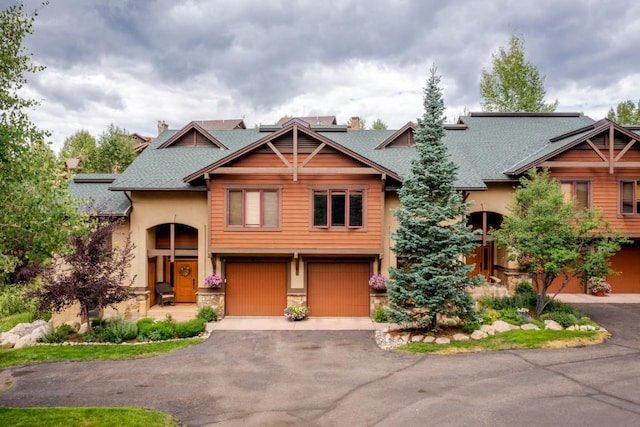 2755 Waterstone Ln Unit 35, Steamboat Springs, CO 80487 - view of front facade featuring asphalt driveway, stone siding, an attached garage, a shingled roof, and a chimney
