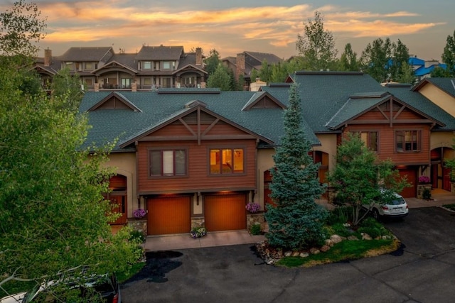 2755 Waterstone Ln Unit 35, Steamboat Springs, CO 80487 - view of front of home featuring a garage, asphalt driveway, a residential view, stone siding, and a shingled roof